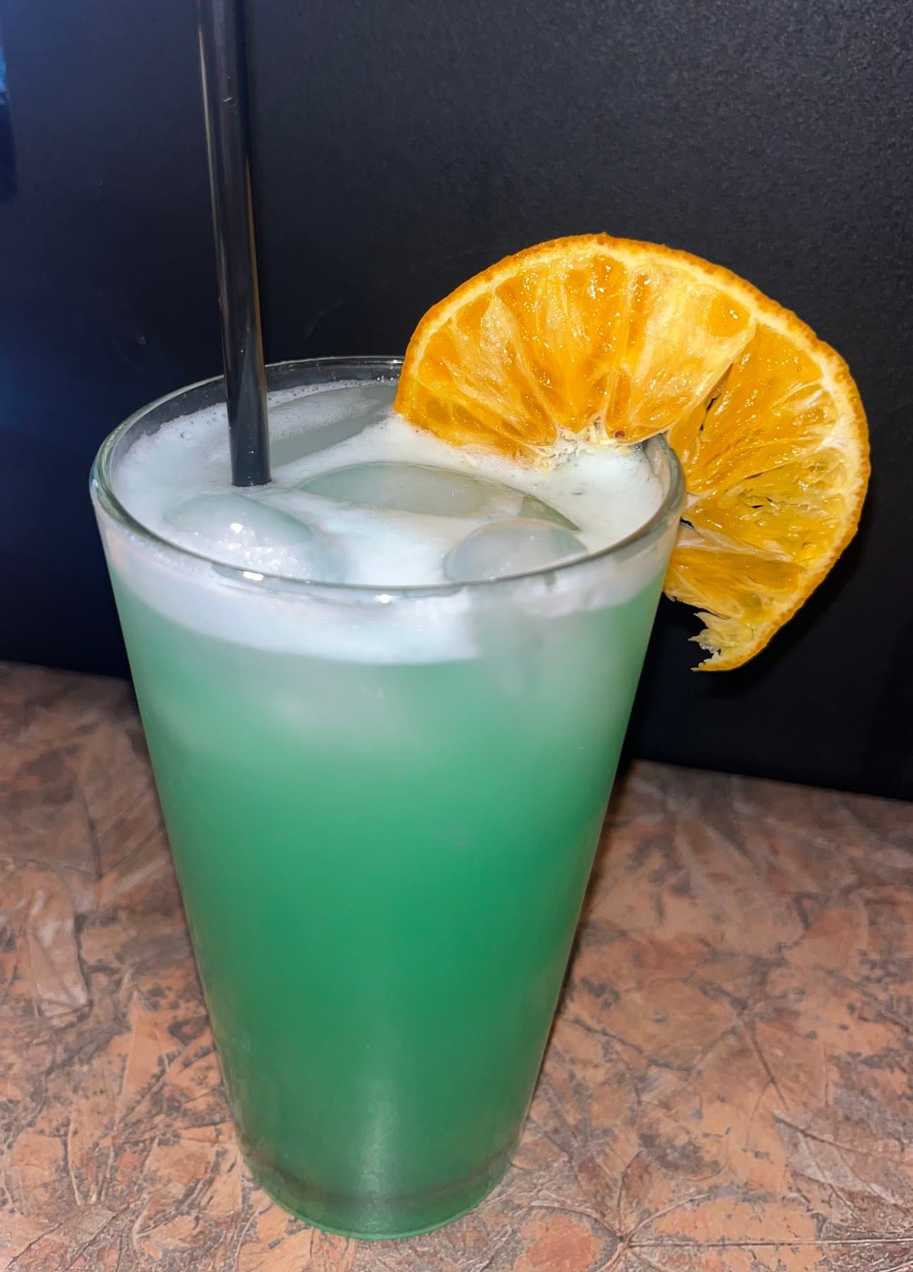 Green Plasma Infusion mocktail with orange garnish